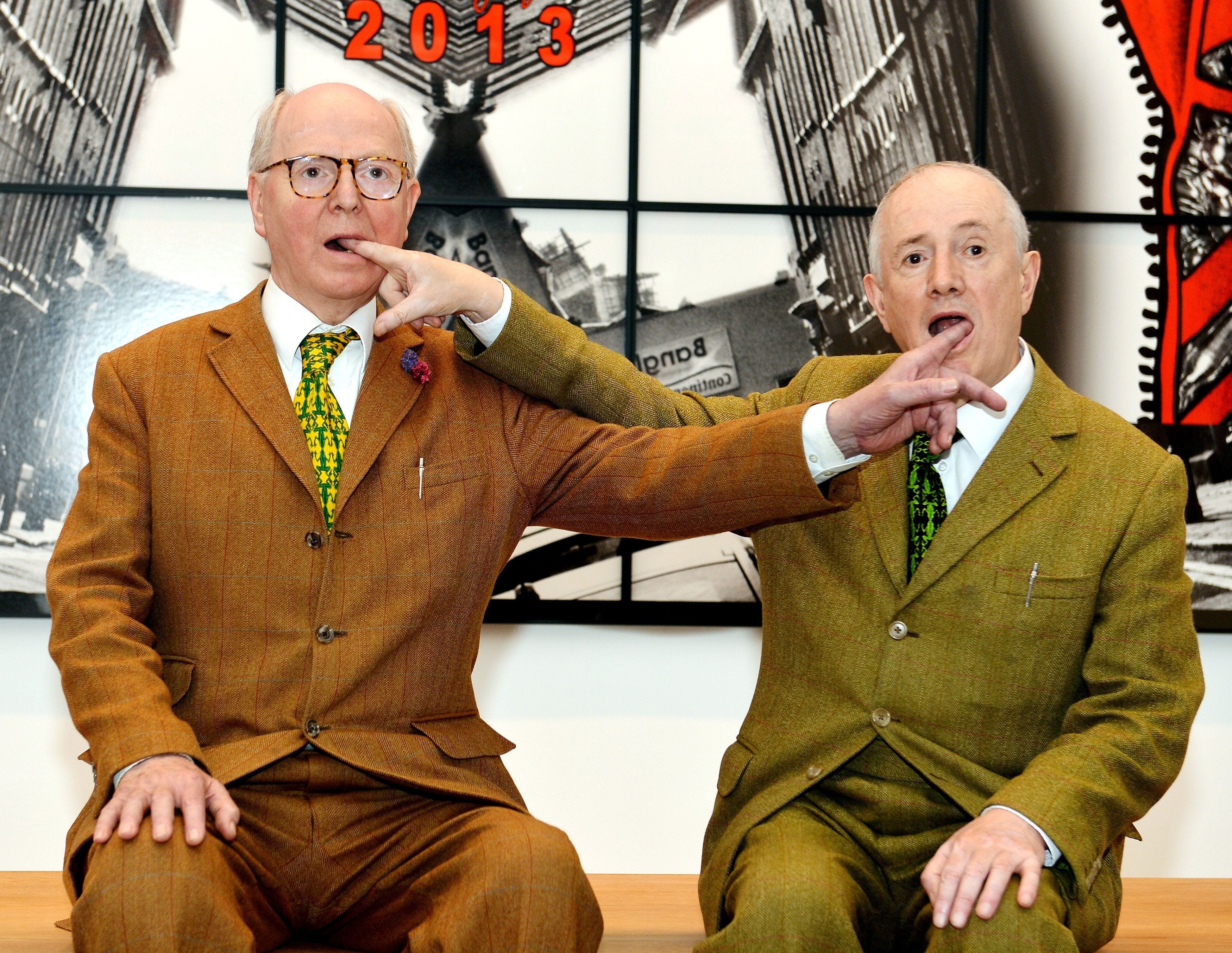 gilbert_george_sit_in_front_of_their_artwork_city_lights_news_photo