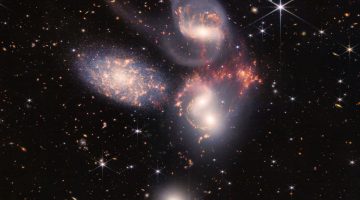 An enormous mosaic of Stephan’s Quintet is the largest image to date from NASA’s James Webb Space Telescope, covering about one-fifth of the Moon’s diameter. It contains over 150 million pixels and is constructed from almost 1,000 separate image files. The visual grouping of five galaxies was captured by Webb’s Near-Infrared Camera (NIRCam) and Mid-Infrared Instrument (MIRI).
With its powerful, infrared vision and extremely high spatial resolution, Webb shows never-before-seen details in this galaxy group. Sparkling clusters of millions of young stars and starburst regions of fresh star birth grace the image. Sweeping tails of gas, dust and stars are being pulled from several of the galaxies due to gravitational interactions. Most dramatically, Webb’s MIRI instrument captures huge shock waves as one of the galaxies, NGC 7318B, smashes through the cluster. These regions surrounding the central pair of galaxies are shown in the colors red and gold.
This composite NIRCam-MIRI image uses two of the three MIRI filters to best show and differentiate the hot dust and structure within the galaxy. MIRI sees a distinct difference in color between the dust in the galaxies versus the shock waves between the interacting galaxies. The image processing specialists at the Space Telescope Science Institute in Baltimore opted to highlight that difference by giving MIRI data the distinct yellow and orange colors, in contrast to the blue and white colors assigned to stars at NIRCam’s wavelengths. 
Together, the five galaxies of Stephan’s Quintet are also known as the Hickson Compact Group 92 (HCG 92). Although called a “quintet,” only four of the galaxies are truly close together and caught up in a cosmic dance. The fifth and leftmost galaxy, called NGC 7320, is well in the foreground compared with the other four. NGC 7320 resides 40 million light-years from Earth, while the other four galaxies (NGC 7317, NGC 7318A, NGC 7318B, and NGC 7319) are about 290 million light-years away. This is still fairly close in cosmic terms, compared with more distant galaxies billions of light-years away. Studying these relatively nearby galaxies helps scientists better understand structures seen in a much more distant universe.
This proximity provides astronomers a ringside seat for witnessing the merging of and interactions between galaxies that are so crucial to all of galaxy evolution. Rarely do scientists see in so much exquisite detail how interacting galaxies trigger star formation in each other, and how the gas in these galaxies is being disturbed. Stephan’s Quintet is a fantastic “laboratory” for studying these processes fundamental to all galaxies.
Tight groups like this may have been more common in the early universe when their superheated, infalling material may have fueled very energetic black holes called quasars. Even today, the topmost galaxy in the group – NGC 7319 – harbors an active galactic nucleus, a supermassive black hole that is actively accreting material.
In NGC 7320, the leftmost and closest galaxy in the visual grouping, NIRCam was remarkably able to resolve individual stars and even the galaxy’s bright core. Old, dying stars that are producing dust clearly stand out as red points with NIRCam.
The new information from Webb provides invaluable insights into how galactic interactions may have driven galaxy evolution in the early universe.
As a bonus, NIRCam and MIRI revealed a vast sea of many thousands of distant background galaxies reminiscent of Hubble’s Deep Fields.
NIRCam was built by a team at the University of Arizona and Lockheed Martin’s Advanced Technology Center.
MIRI was contributed by ESA and NASA, with the instrument designed and built by a consortium of nationally funded European Institutes (The MIRI European Consortium) in partnership with JPL and the University of Arizona.
For a full array of Webb’s first images and spectra, including downloadable files, please visit: https://webbtelescope.org/news/first-images